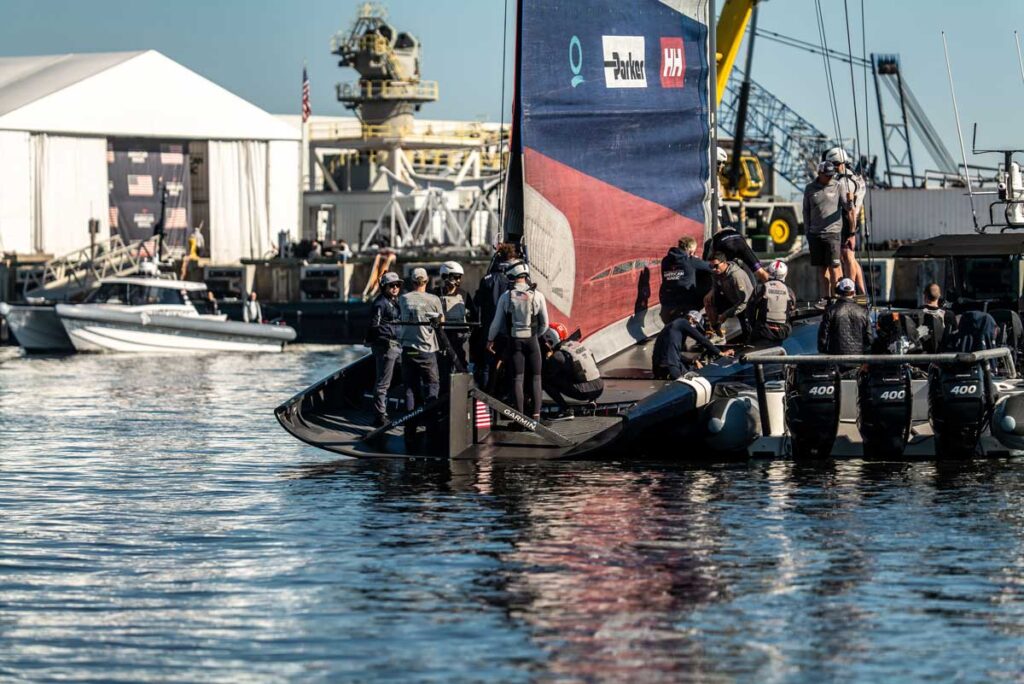 The American Magic Team prepares its raceboat at the dock in Pensacola, Florida with sailors inspecting a new piece of equipment