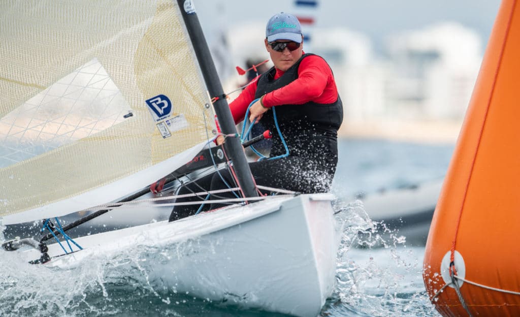 Finn dinghy sailor Joan Cardona, sailing past an orange racing bouy.