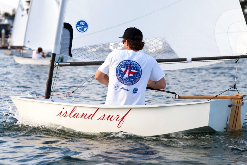 A man pilots a sailboat dinghy.