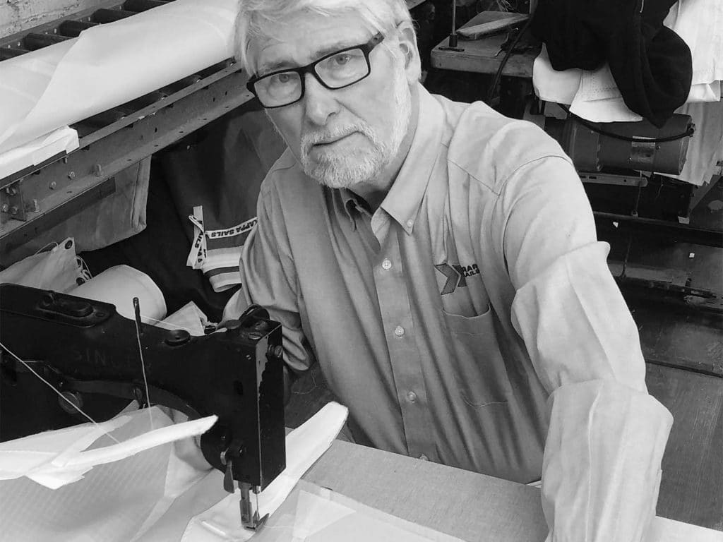 A black and white image of a man at a sewing machine.